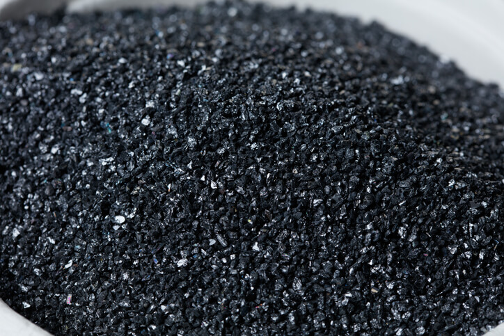Gros plan sur de fines particules de carbure de silicium, sur fond blanc, matériau indispensable à l'infrastructure IA.