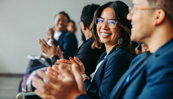 Divers collègues applaudissant et souriant lors d'un salon IA ou d'une conférence IA en automne 2026. Crédits iStock : jacoblund Référence de la photo : 2162383390