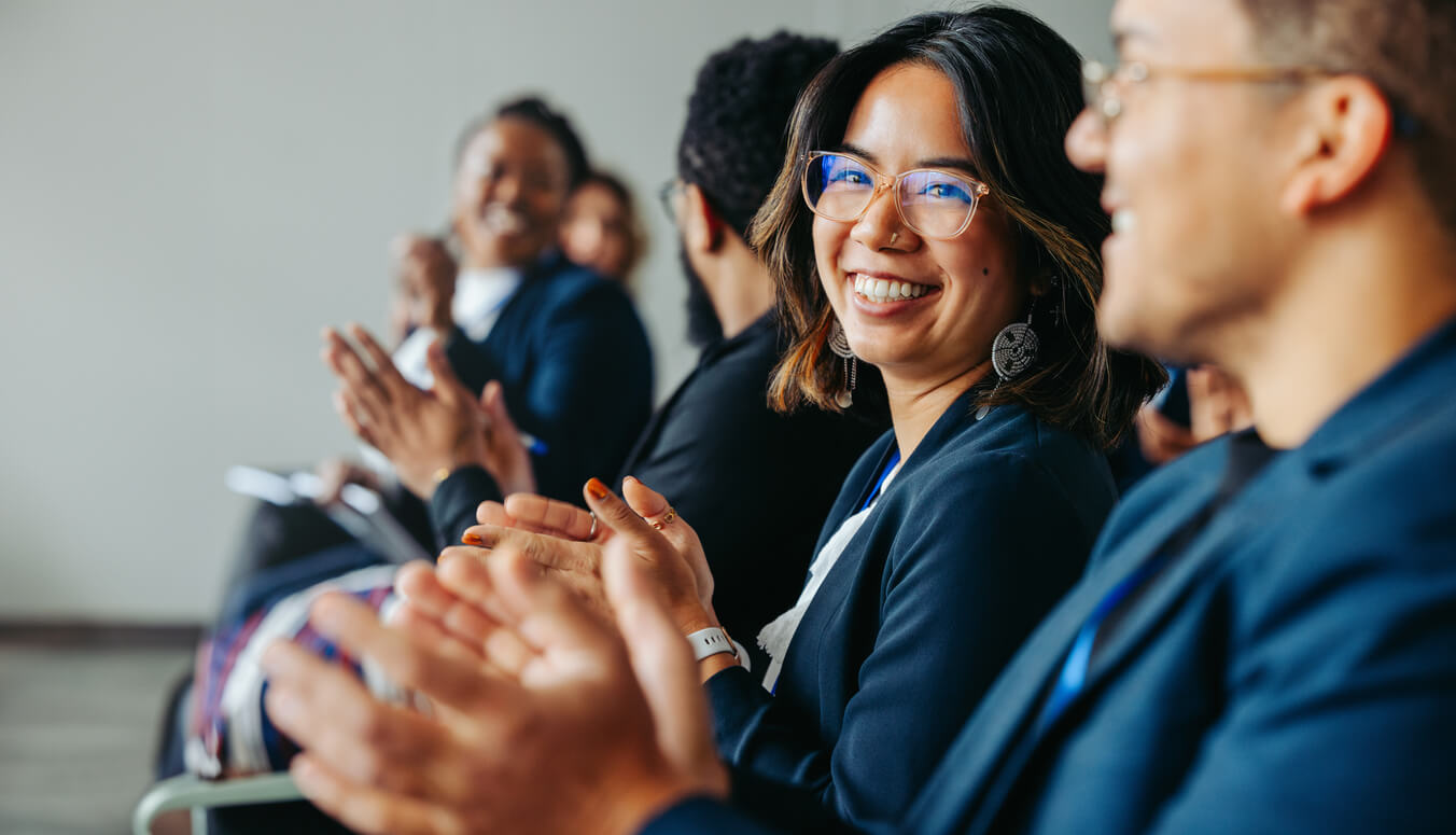 Divers collègues applaudissant et souriant lors d'un salon IA ou d'une conférence IA en automne 2026. Crédits iStock : jacoblund Référence de la photo : 2162383390